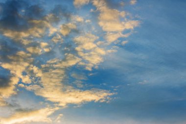 Gün batımında mavi gökyüzünde altın bulutlar