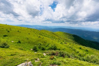 Gökyüzünde bulutlar olan dağlardaki yeşil çayırlar