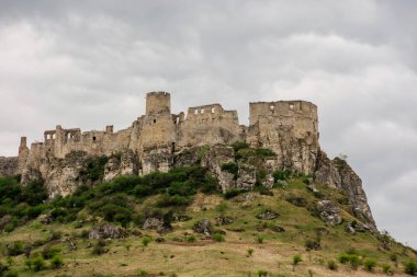Baharda bulutlu bir günde Spis Kalesi 'nin kalıntıları. Slovakya 'nın ünlü seyahat yeri. Unesco mirası. Tepenin eteğindeki çimenli çayır.
