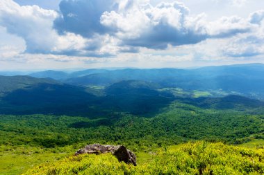 Dağın tepesinden vadiye bak. Çimenli yamaçtaki dev kayalar. Gökyüzündeki bulutlar. Işıklı güzel güneşli bir hava. Turizm kavramında özgürlük