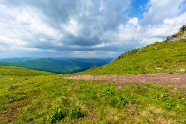 Dağ sırasına giden yol. Yazın bulutlu bir günde Karpatlar 'ın güzel dağlık çayırları. Havza sırtı bölme