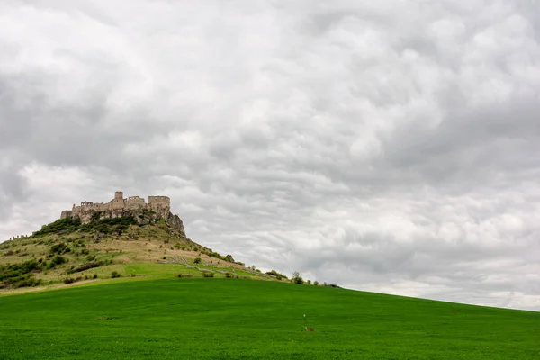 ruins of spis castle on a cloudy day in springtime. famous travel destination of slovakia. UNESCO heritage. grassy meadow at the foot of the hill.