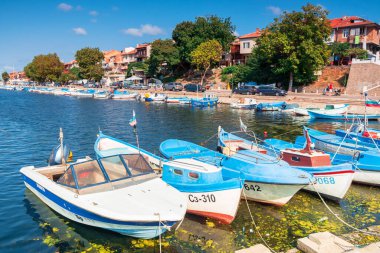 Sozopol, Bulgaria - Sep 09, 2019: güneşli bir günde limanda balıkçı tekneleri. Manzaranın arka planında toprak seti. Sudaki çöp.