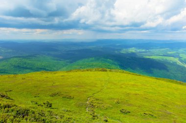 Dağ sırasına giden yol. Yazın bulutlu bir günde Karpatlar 'ın güzel dağlık çayırları. Havza sırtı bölme