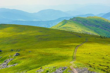 Dağ sırasına giden yol. Yazın bulutlu bir günde Karpatlar 'ın güzel dağlık çayırları. Havza sırtı bölme