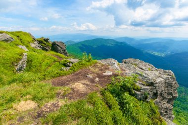 Dağın tepesinden vadiye bak. Çimenli yamaçtaki dev kayalar. Gökyüzündeki bulutlar. Işıklı güzel güneşli bir hava. Turizm kavramında özgürlük