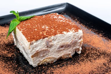Siyah tabakta tiramisu keki. Naneli İtalyan tatlısı.