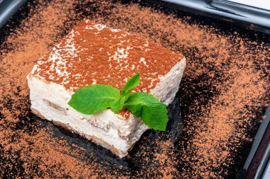 Siyah tabakta tiramisu keki. Naneli İtalyan tatlısı.