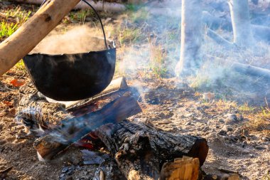 Dışarıda eski otları tüttürüyorum. Yemek yapmak ve kamp yapmak. Açık hava maceraları konsepti. Kamp ateşinde dövülmüş kazan