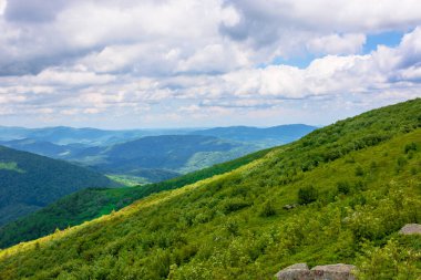 Yazın harika bir dağ manzarası. Doğada yeşil ve mavi renkler varsa güzellik. Dinamik bir gökyüzünün altındaki benekli ışıkta sersemletici dağ manzarası.
