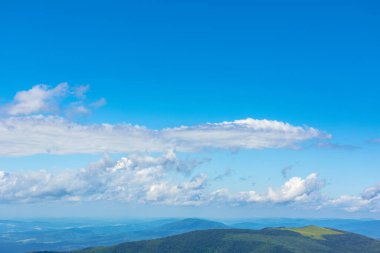 Mavi gökyüzünde beyaz kabarık bulutlar. Dağlardaki güzel doğa manzarası