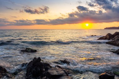 Gün batımında okyanus kıyısında. Suda kayalar olan güzel bir manzara. Güneş ve ufuktaki muhteşem bulutlar. sakinlik ve arabuluculuk kavramı