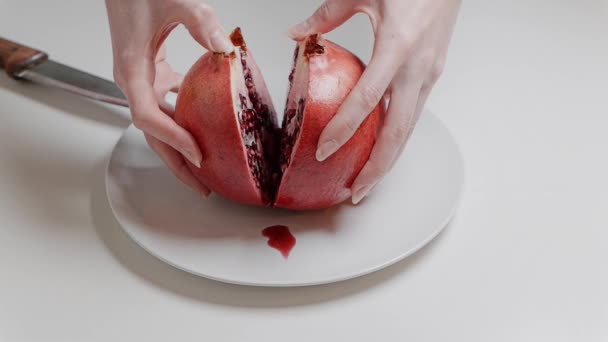 Les mains féminines cassent la grenade en deux, gros plan au ralenti 