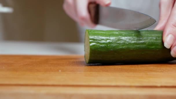 Gros plan de mains féminines coupant un concombre sur une planche de bois dans une cuisine moderne. Une alimentation saine. Macro. Préparer une salade — Video