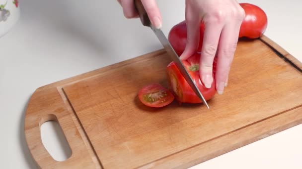 Gros plan de la main de tomate fraîche de coupe femelle à l'aide d'un couteau de cuisine sur une planche à découper en bois — Video