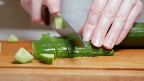 Gros plan de mains féminines coupant un concombre sur une planche de bois — Video