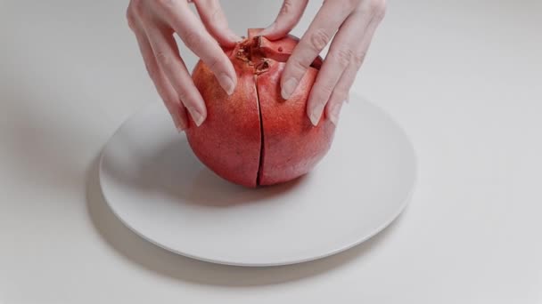 Les mains féminines cassent la grenade en 4 parties, gros plan au ralenti 