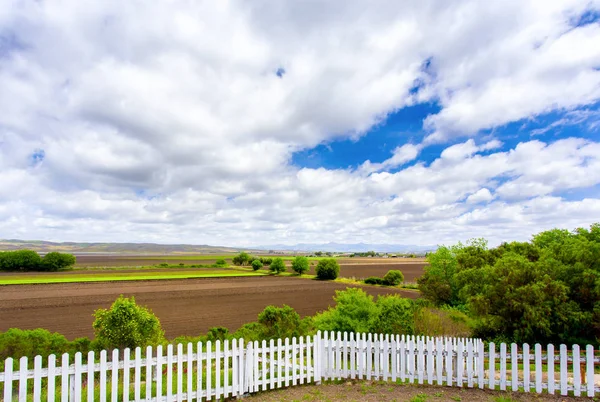 Fehér Előőrs kerítés, a termőföld és a felhők — Stock Fotó