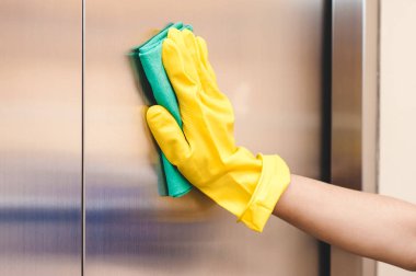 Bir elinde bir sarı lastik eldiven sarı bir bezle Asansör yıkar