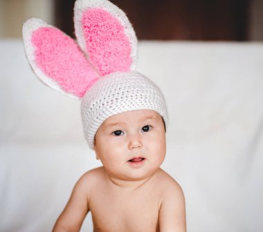 Beyaz arka plan üzerinde tavşan kulaklı şapkalı Asya bebek portresi