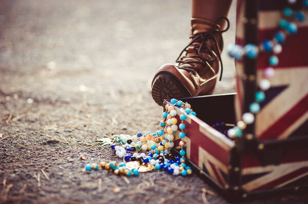 Female foot in boot on an open suitcase with jewelry