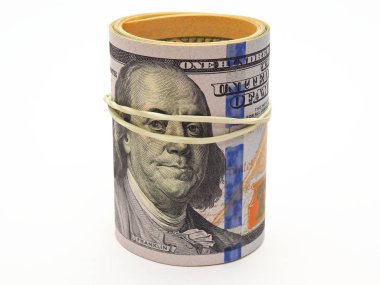 Bir paket dolar sarılır, elastik bir bantla bir araya getirilir ve beyaz arka planda durur. İzole değil. 100 dolarlık banknotun üstü renkli, yeni bir örnek. Para masanın altında. Makro