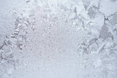 Kışın pencere camında buz ve buz. Şablon sihirli bir bitki gibi. Hava tahmini: soğuk, buz gibi, serinliyor. Soyut gizemli ışık arkaplanı. Zor bir mevsim. Düşük karşıtlık