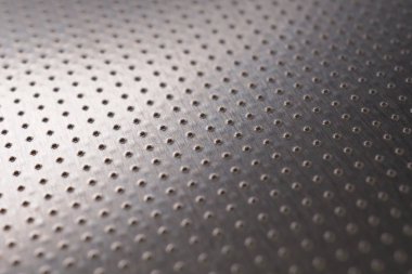 Birçok deliği olan alüminyum yüzey. Safları uzaklaşıyor ve bir perspektif oluşturuyor. Soyut koyu gri metal arka plan veya duvar kağıdı. Makro
