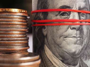 Eski usul 100 dolarlık banknotlar ve Amerikan çeyreklikleri. Banknotlar toplanır ve elastik bir bantla bir araya getirilir. Dramatik illüstrasyon. Kayıt dışı para masanın altında. Makro