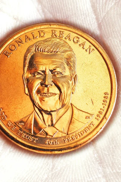 US coin lies on the palm. Obverse coins featuring President Reagan. American political system, presidential elections. Republican party electoral fund contributions. 1 dollar. Vertical shot. Macro