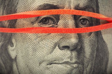 100 dolarlık banknot çok yakın. Franklin 'in yüzü maske gibi lastik bir bantla kaplı. Amerikan ekonomisi ve devalüasyonuyla ilgili haberler. Gözetleme, sade anahtar. Makro