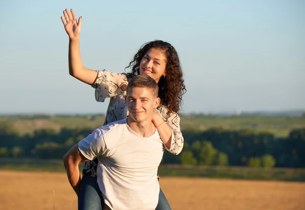 Gelukkige jonge paar lopen op land mensen van buiten, Romantisch concept, zomerseizoen, meisje rijden op man rug en zwaaien — Stockfoto