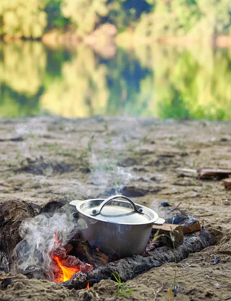 Vaření na ohni na piknik, jídlo připravené v konvici pouze na dřevo, stromy odráží v řece, zdravé vegetariánské jídlo — Stock fotografie