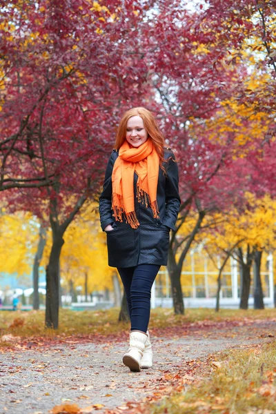 Passeggiata ragazza sul sentiero nel parco della città con alberi rossi, stagione autunnale — Foto Stock
