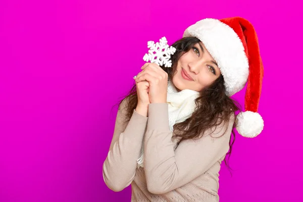 Niña en retrato de sombrero de santa con gran juguete de copo de nieve posando sobre fondo de color rosa, concepto de vacaciones de Navidad, feliz y emociones — Foto de Stock