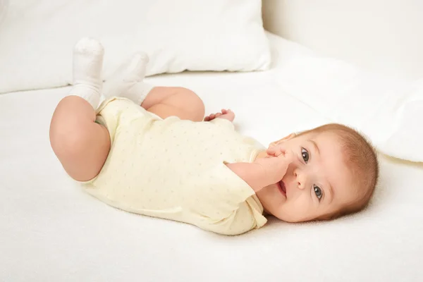 Baby portrait lie on white towel in bed, yellow toned — Stock Photo, Image