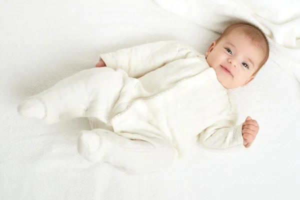 Baby portait lie on white towel in bed, yellow toned — Stock Photo, Image