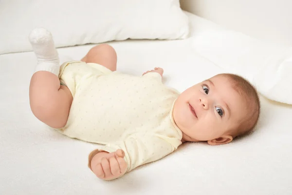 Baby portrait lie on white towel in bed, yellow toned — Stock Photo, Image