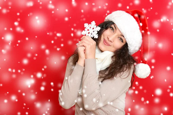 Mädchen mit Weihnachtsmütze Porträt mit großen Schneeflocken Spielzeug posiert auf rotem Hintergrund, Weihnachtsurlaub Konzept, glücklich und Emotionen — Stockfoto