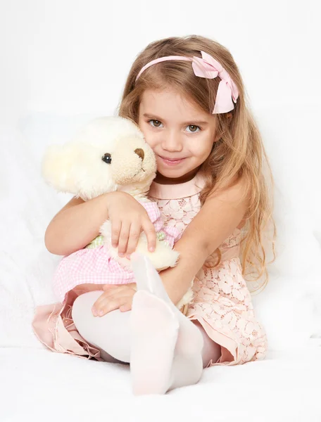 Adorable little child girl sit in the bed with her toy. The child girl hugs the teddy bear. — Stock Photo, Image