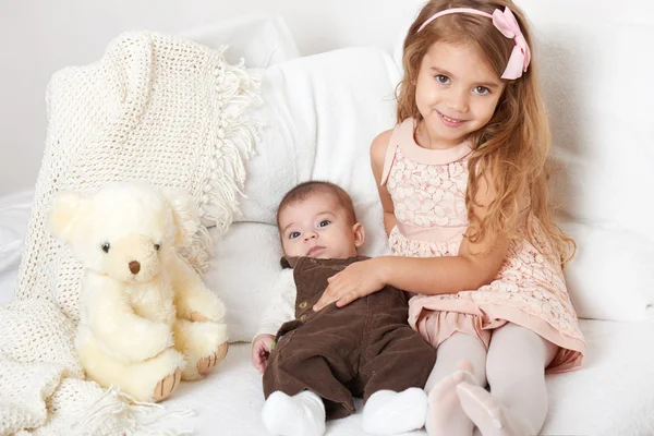 Adorable little child girl and boy sit in the bed with teddy bear — Stock Photo, Image