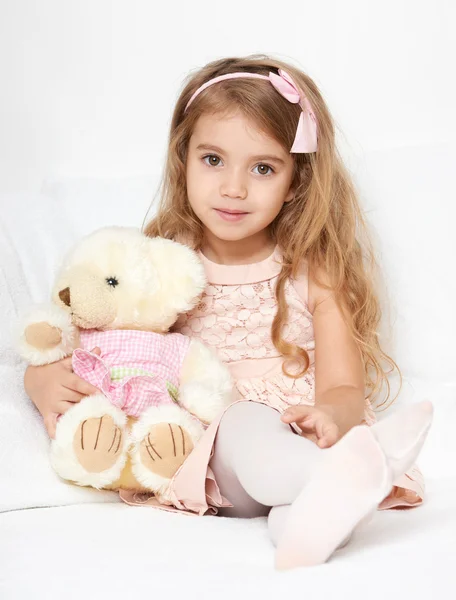 Menina adorável criança sentar-se na cama com seu brinquedo. A menina abraça o ursinho de pelúcia . — Fotografia de Stock