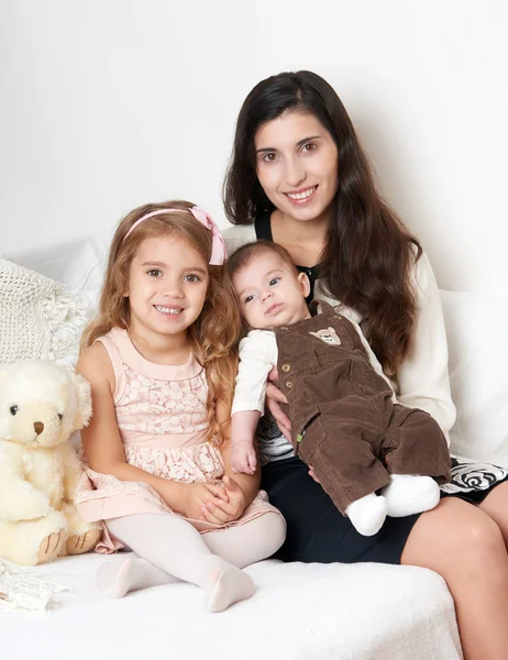 Mutter mit ihren Kindern im Bett mit Teddybär, glückliches Familienporträt — Stockfoto