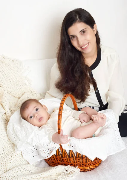 Madre con el bebé en la cesta en la cama, retrato familiar feliz sobre fondo blanco — Foto de Stock