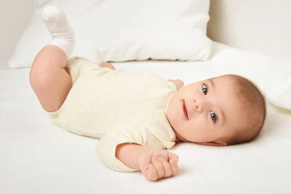 Babyporträt liegt auf weißem Handtuch im Bett, gelb getönt — Stockfoto