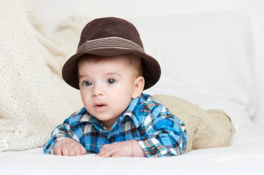 Bebek portre yalan yatakta ekose gömlek ve şapka giymiş beyaz havlu üzerine