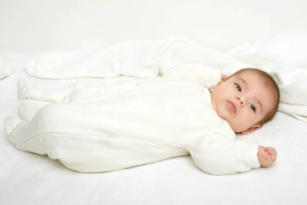 Baby on white towel in bed, yellow toned — Stock Photo, Image