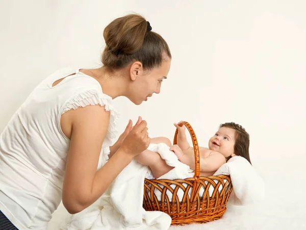 Мать говорить с ребенком в корзине на белом полотенце, семейная концепция, желтый тонус — стоковое фото