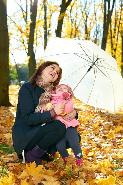 Mujer con niña bajo el paraguas en el parque de otoño de la ciudad, familia feliz —  Fotos de Stock