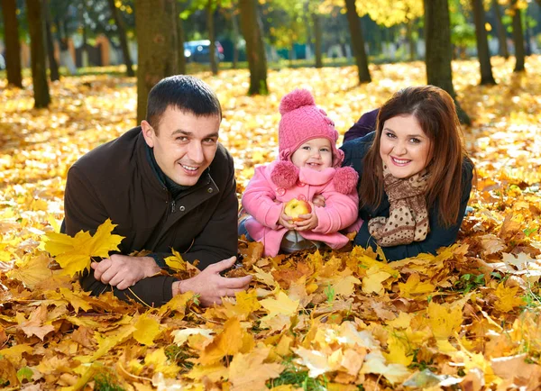Familia feliz se encuentran en hojas amarillas en el parque de otoño de la ciudad — Foto de Stock